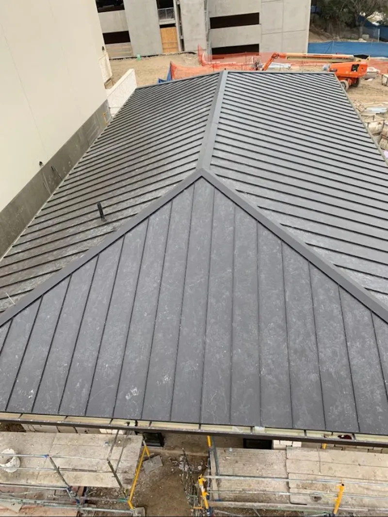 Commercial metal roof construction with crane equipment in Turner